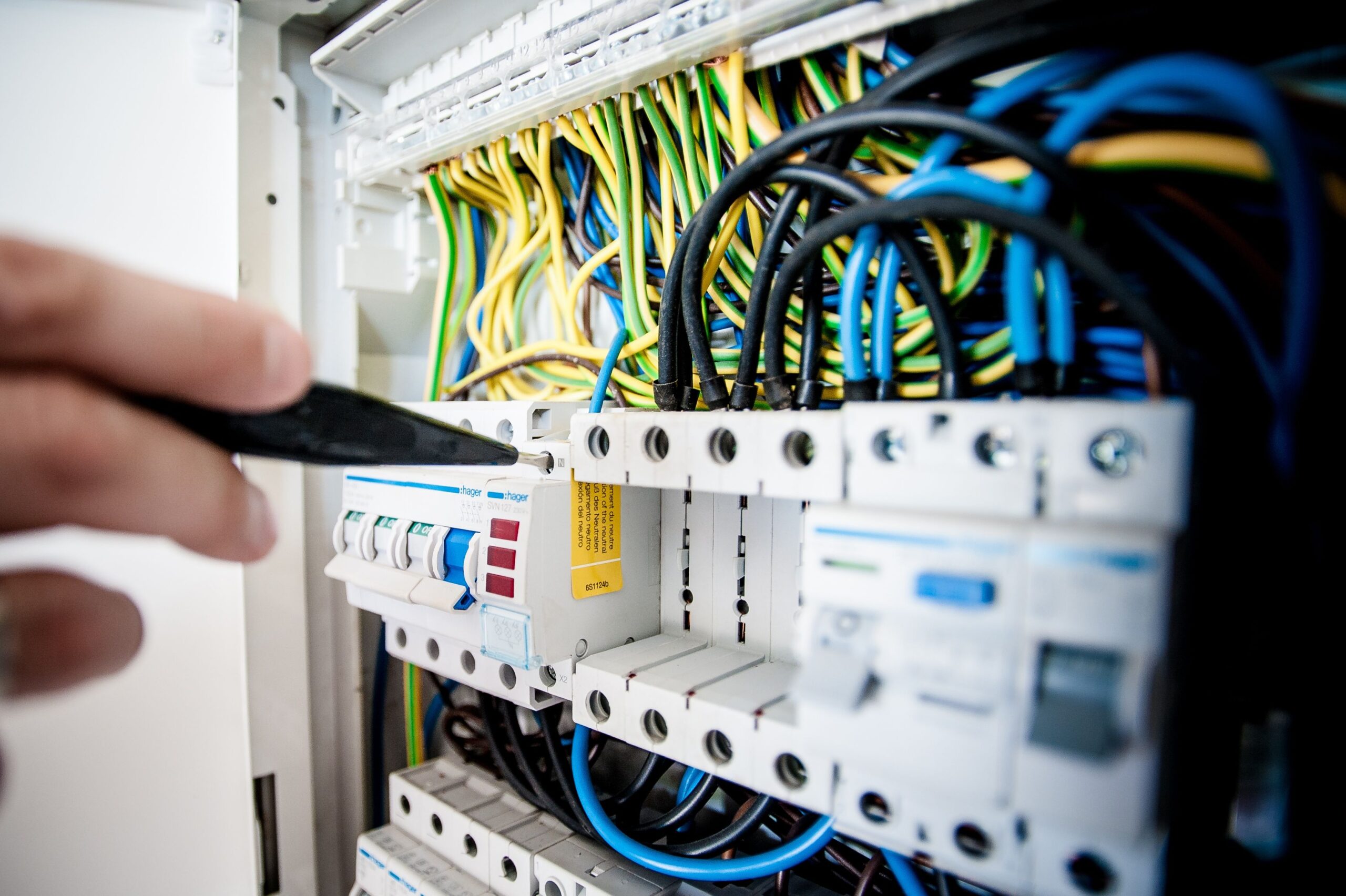 About Hand of electrician working on a circuit breaker panel with colorful wires, ensuring safe electrical connections.